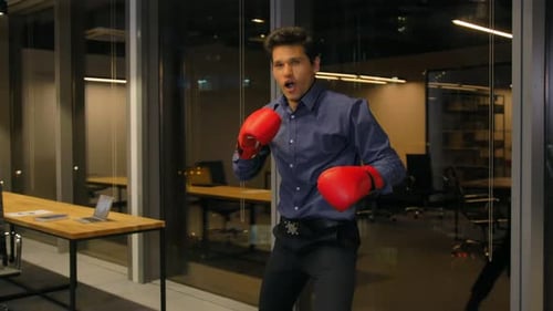 Businessman in Boxing Gloves Punching in Modern Office