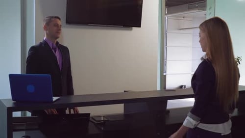 Frau mit Gepäck im Gespräch mit Arbeiterin in Lobby