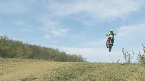Dirt Bike Jumps Over Hill in Rural Landscape