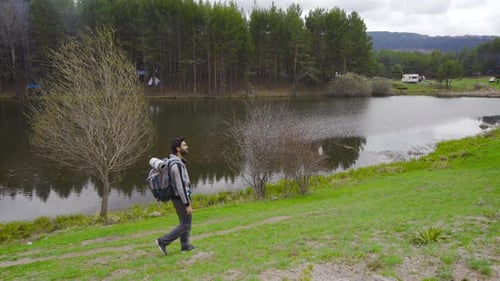 Lone Hiker with Backpack Walking by Peaceful Lake