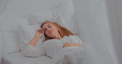 Woman Waking Up and Stretching in White Bed