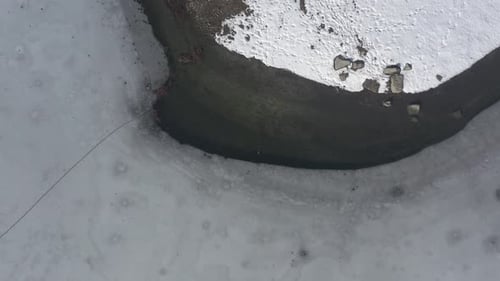 Neige sur la côte et glace sur la surface de l'eau du lac (vidéo aérienne 4K)