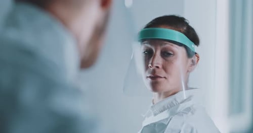 Woman in Lab Coat and Face Shield Talking