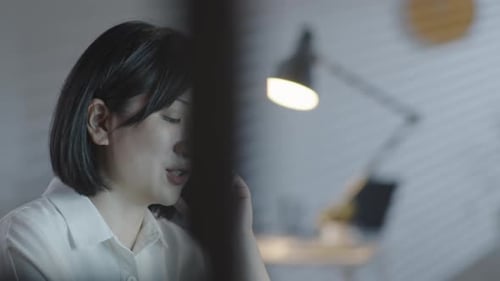 Businesswoman Making Phone Call in Office in Evening