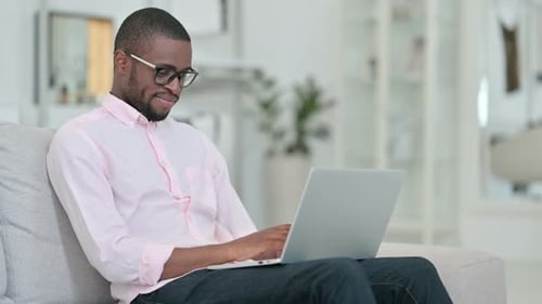Man Working on Laptop at Home, Smiling