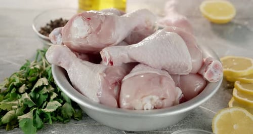 Raw Chicken Legs and Herbs in a Bowl