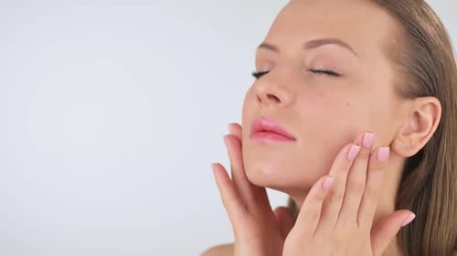 Woman Massages Face Cream Onto Cheeks, Close Up