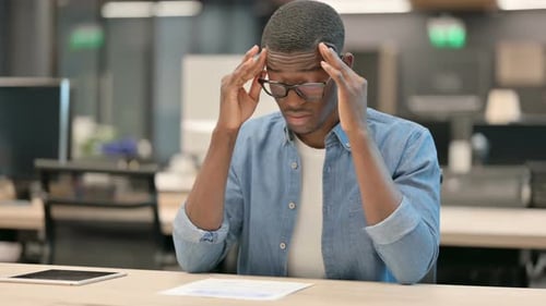 Young African American Man Having Headache While Sitting in Office