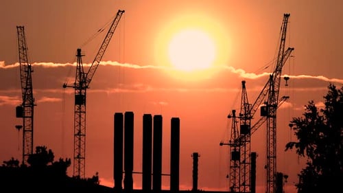 Construction Cranes Silhouetted Against a Vibrant Sunrise