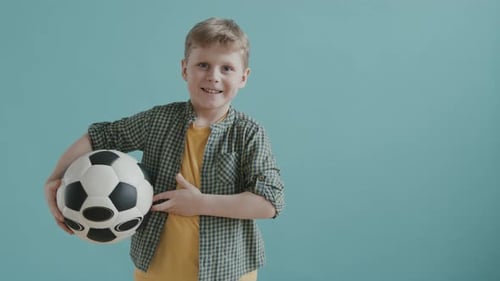 Smiling Young Boy Holding Soccer Ball Indoors