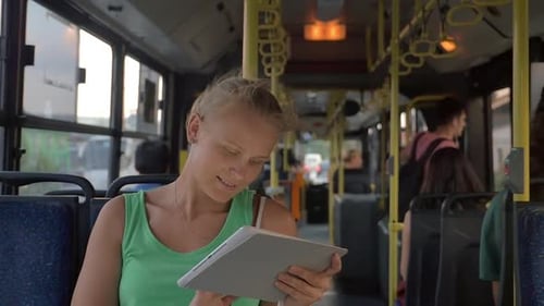 Smiling Woman Typing in Tablet in the Bus