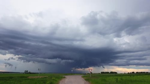 Dramatic Sky With Rain Clouds On Horizon Above Rural Landscape Country Road Through Field