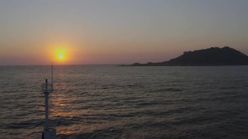 A romantic scenery where the setting sun illuminates the lighthouse and island