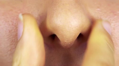 Una mujer aprieta su nariz - Closeup
