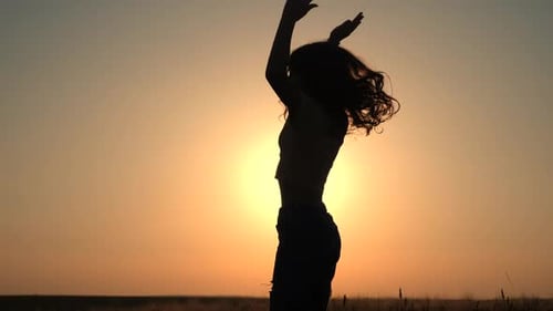 Girls enjoy nature, jumping, dancing in fields on sunset. Slow motion.
