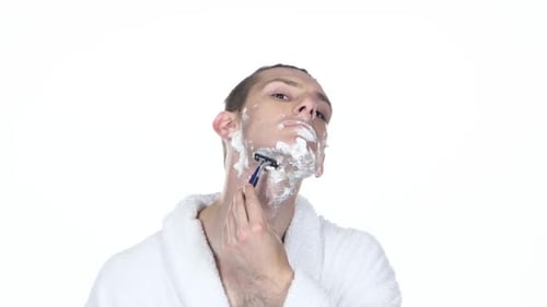 Young Man Shaving Beard with Razor at Home