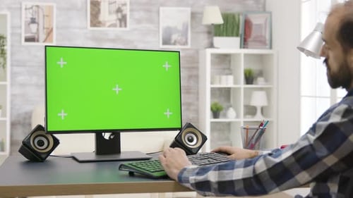 Man Works on Isolated Green Screen PC Display in Bright, Well Lit Living Room