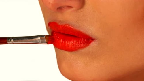 Young Woman Applying Red Lipstick By Brush, Close Up