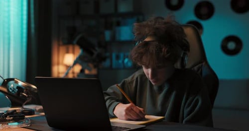 Teen Studying at Night with Laptop and Headphones