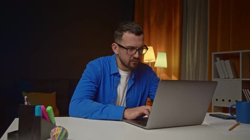Young Adult Typing on Laptop at Night