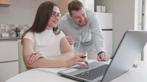 Cheerful Couple Using Laptop in Modern Kitchen