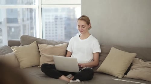 Young Woman Using Laptop on Sofa at Home