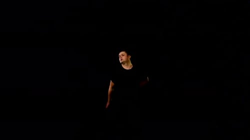Man Juggling Bottles in a Dark Studio