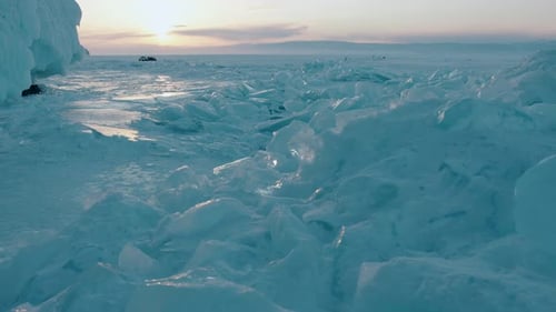 Bluewhite Blocks of Transparent Ice on Frozen Lake Baikal Shimmer in the Rays of Sunset and Standing