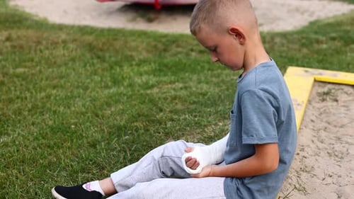 a child's arm is broken. sad little boy with a fractured limb outdoors on the playground. fracture