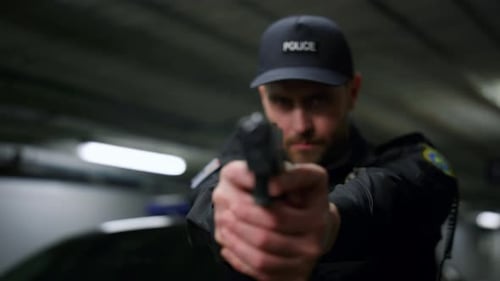 Police Officer Points Gun in Dark Urban Garage