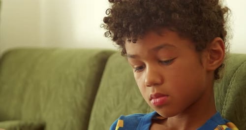 Pensive Boy Sitting on a Couch at Home