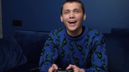 Front View of an Excited Caucasian Man Playing Video Games and Using Joystick Controller. Happy Man