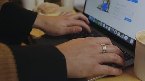 Hands Typing on Laptop Keyboard in Cafe