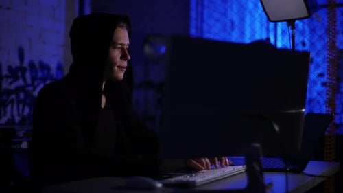 Young Hacker Typing on Computer in Dark Room