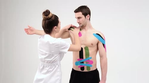 Therapist Applies Athletic Tape to Torso and Shoulder