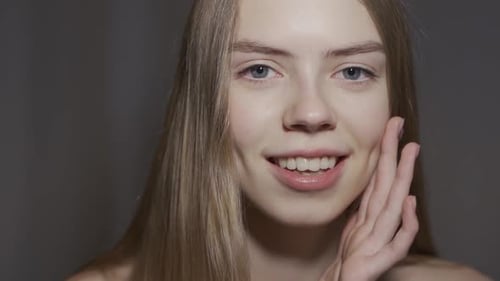 Beautiful Young Woman Smiling and Touching Her Face