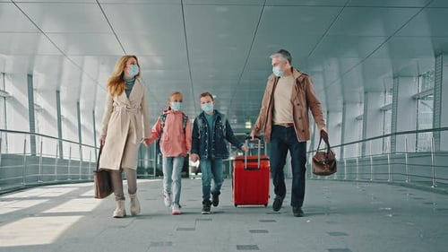 Mother and Father Holding Hands of Their Children and Walking Down Airport Corridor to Flight