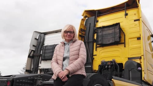 Woman Sits in Front of Yellow Semi Truck