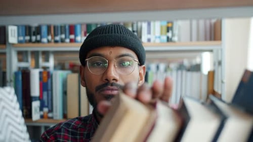 Close-up of African American Man Choosing Books in College Library Smiling