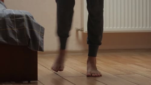 Adult Sitting on Edge of Bed in Bedroom