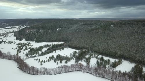 Winterwald und Fluss bei stürmischem Wetter