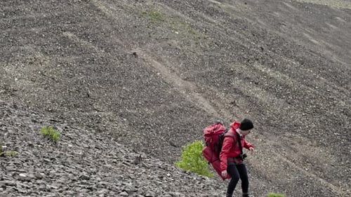 Hiker Climbs Rocky Mountain with Red Backpack