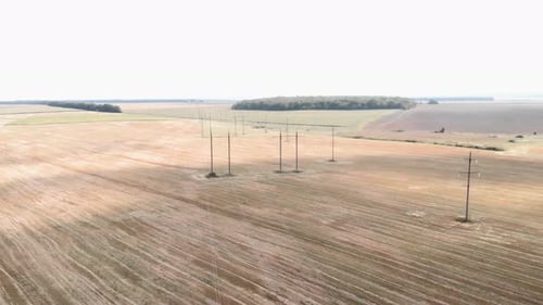 Pylons and power lines in windy field. High voltage power lines