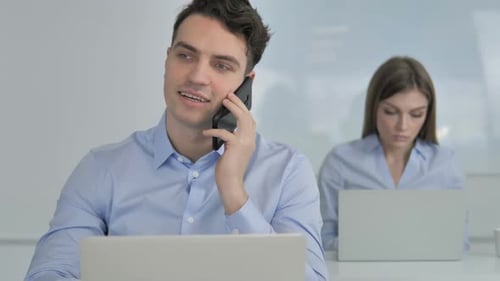 Man Answers Phone While Working on Laptop