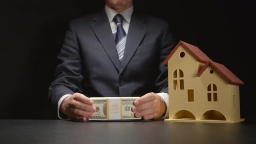Man Stacks Cash Next to a Model House