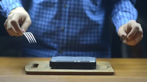 Technician Specialist Is Simulating Cutting of Hard Drive at Table in Service Center. Humor, a Joke
