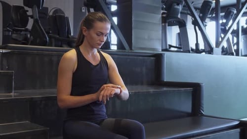 A Fit Girl Turns on a Second Hand Watch for Sports Exercises on a Wristwatch