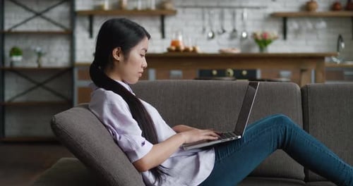 Young Woman Works on Laptop on Living Room Sofa