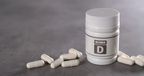 Vitamin D Bottle and Capsules on Gray Surface