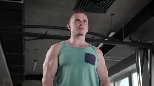 Young man in the gym doing exercises while lifting a pancake from the bar in front of him